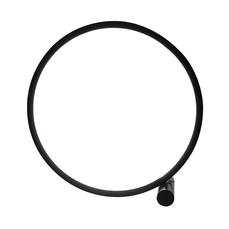 Eine stilvolle 'CircoloLuce' Nachttischlampe in minimalistischem Design leuchtet auf einem Nachttisch, neben einer Vase mit Zweigen.
