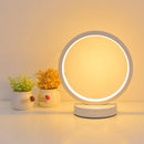 Modern Luce dell'Anello bedside lamp with circular LED light and minimalist design on a bedside table.