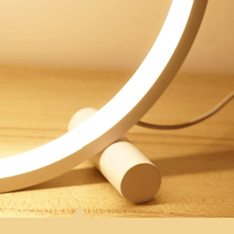 A stylish 'CircoloLuce' bedside lamp in a minimalist design shines on a bedside table, next to a vase with branches.