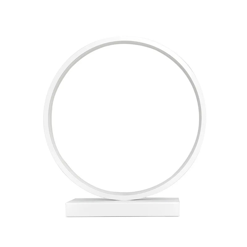 Modern Luce dell'Anello bedside lamp with circular LED light and minimalist design on a bedside table.