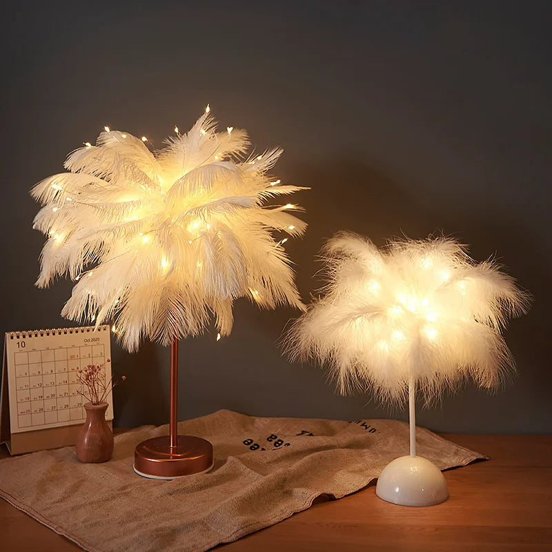 Lampe de chevet 'LuceSoffusa' stylée avec des plumes blanches chaleureusement lumineuses sur un pied en bronze, à côté d'un calendrier, souligné par une télécommande au premier plan.