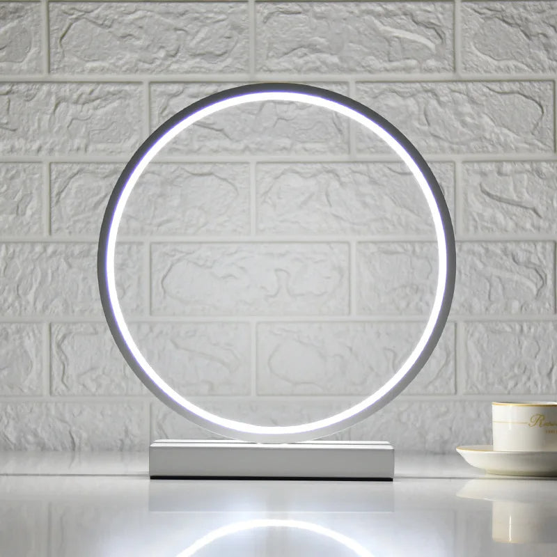 Lampe de chevet Luce dell'Anello moderne avec lumière LED circulaire et design minimaliste sur une table de nuit.